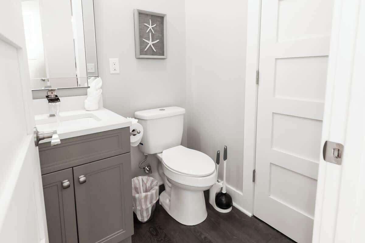 Un bagno con un WC bianco, un lavandino con specchio e un cestino.