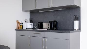 Una cocina moderna con armarios grises, encimera negra y electrodomésticos de acero inoxidable.
