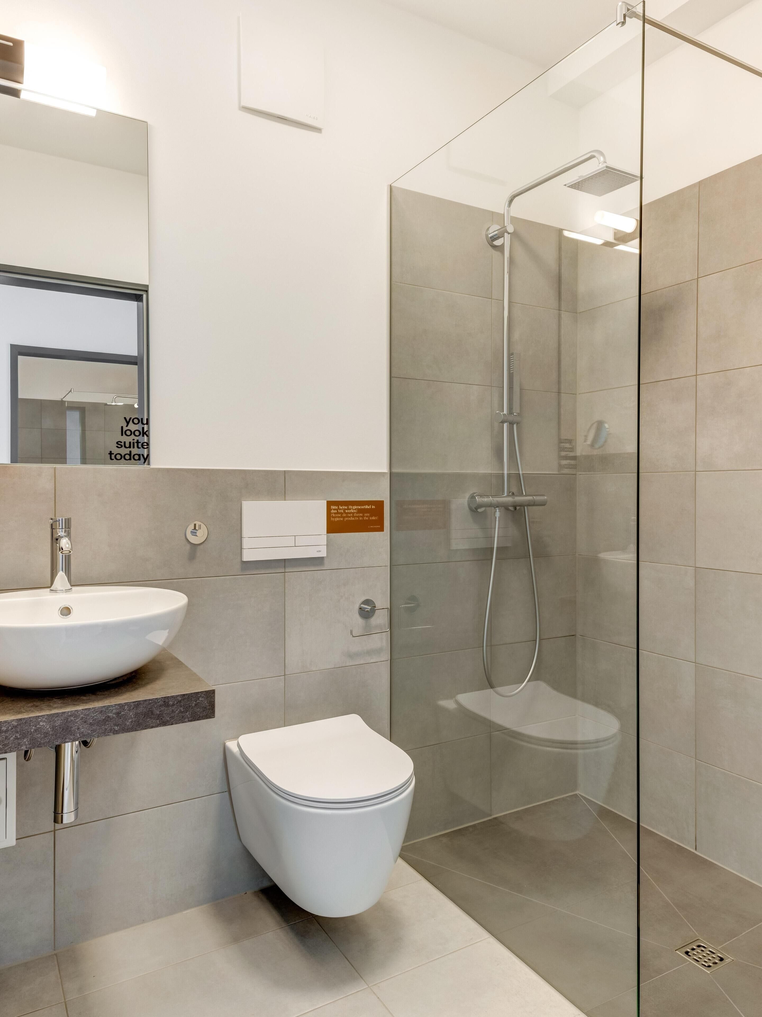 Une salle de bain moderne avec une douche à parois de verre, un lavabo blanc et des toilettes.