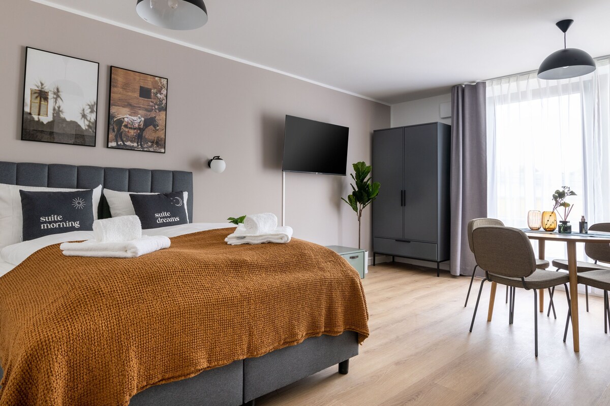 Une chambre d’hôtel comprenant un lit, une télévision, une armoire, une table à manger avec des chaises et des œuvres d’art accrochées aux murs.