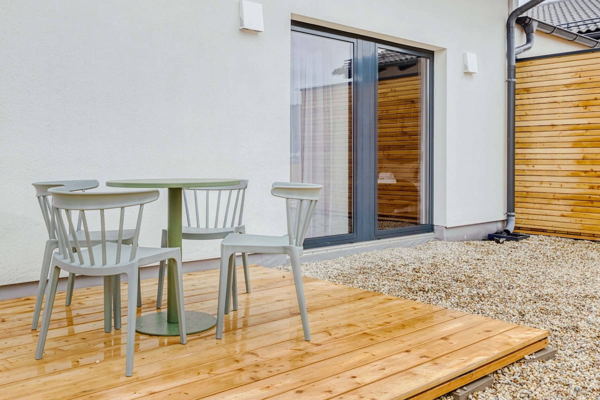 A patio with a wooden deck and white plastic chairs.