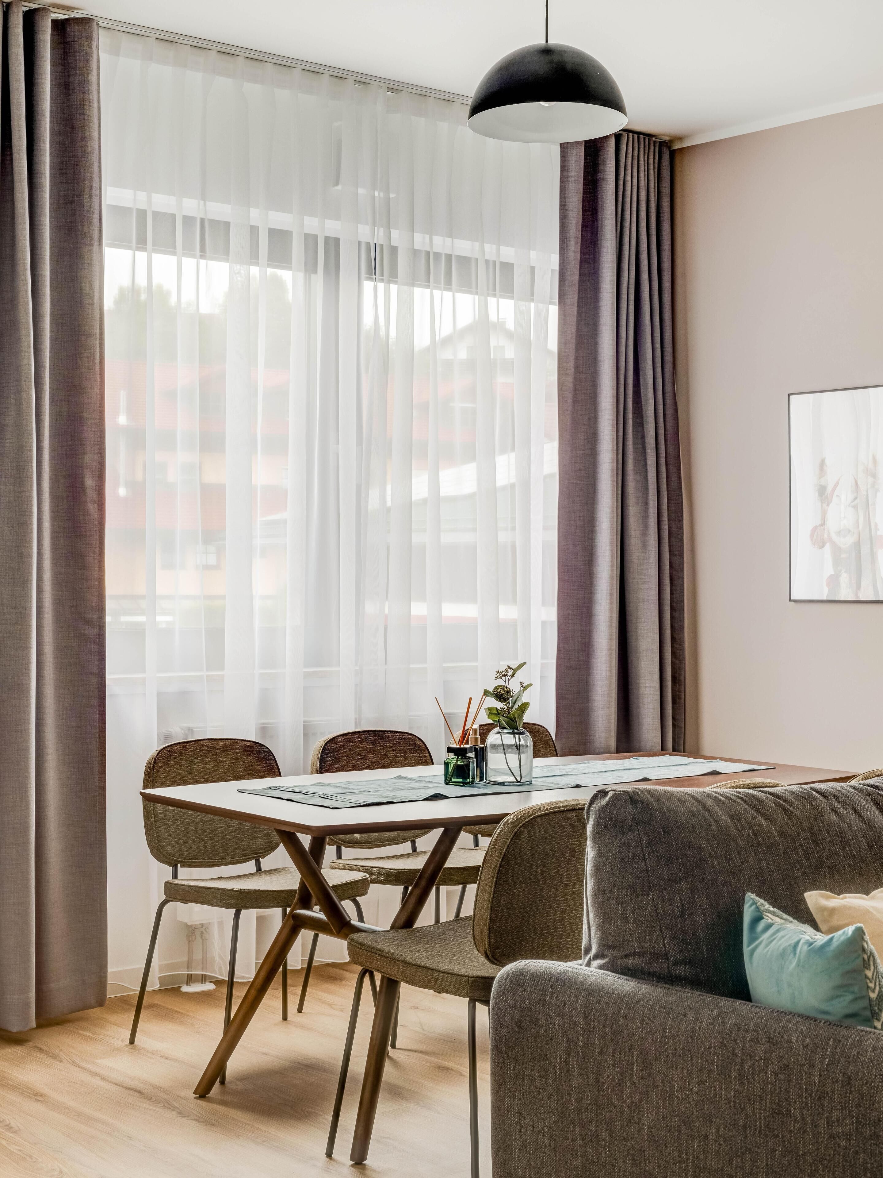 Un espace repas moderne comprenant une table ronde, des chaises, un luminaire suspendu et un canapé.