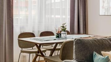 Un espace repas moderne comprenant une table ronde, des chaises, un luminaire suspendu et un canapé.