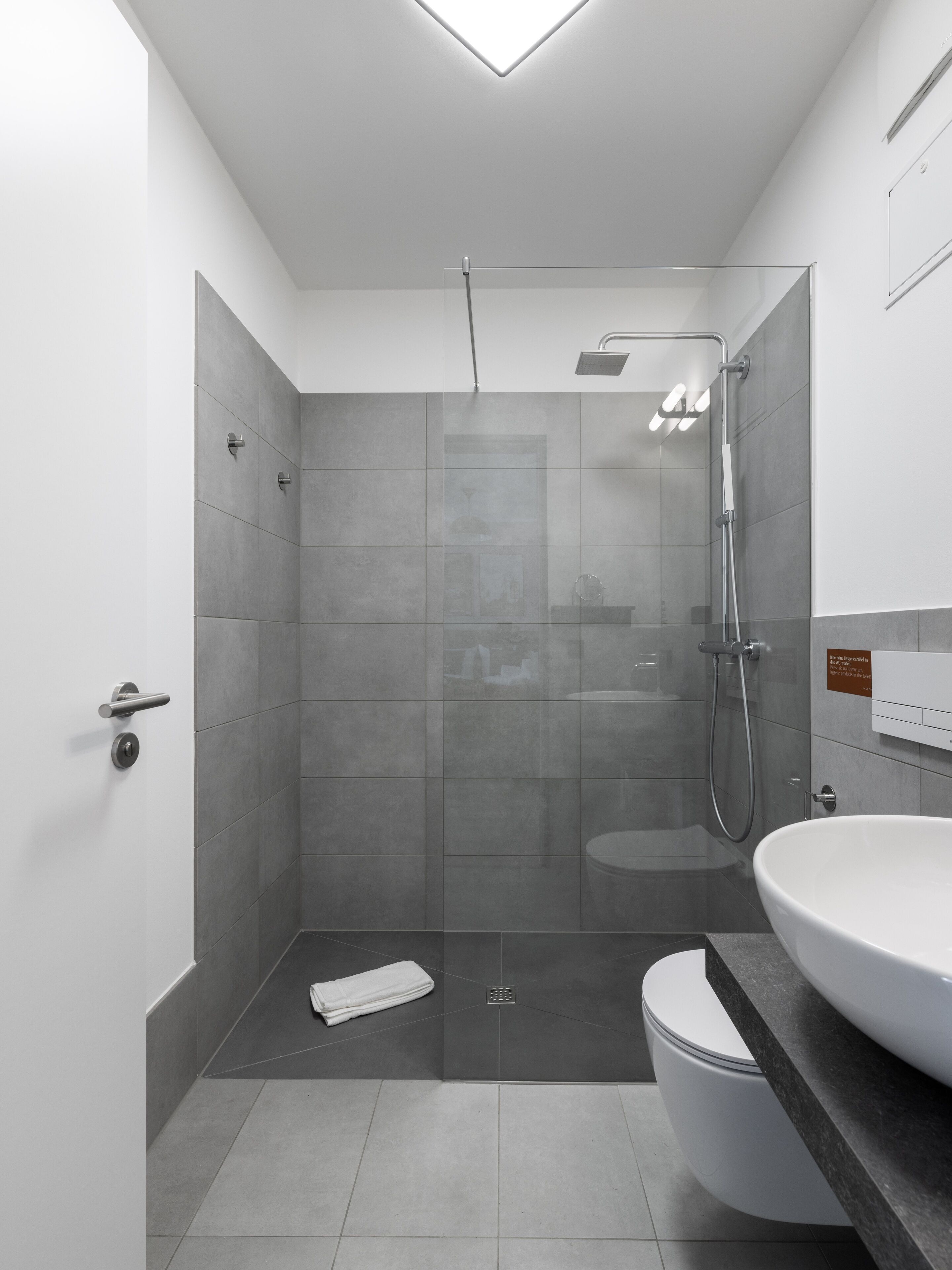 A modern bathroom with a shower, toilet, and sink.