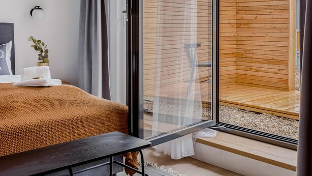 A modern bedroom with a large sliding glass door leading to a wooden deck.