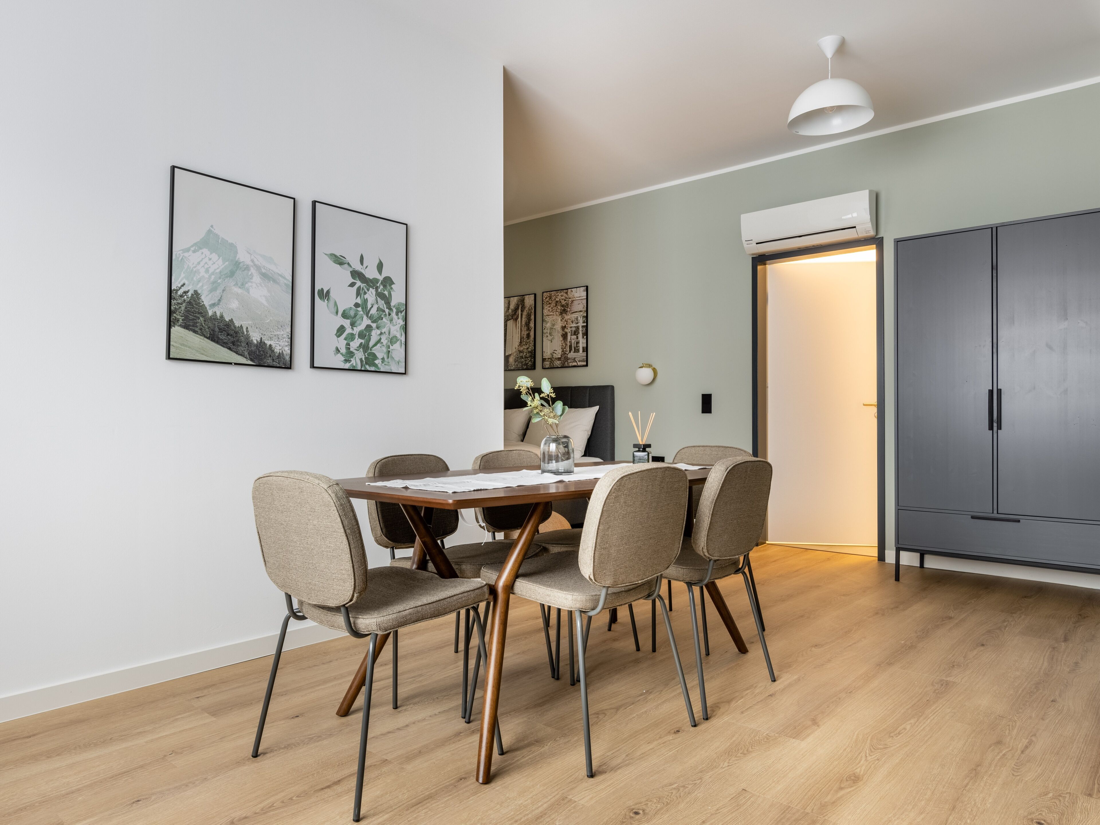 Un comedor con una mesa de madera, seis sillas y cuadros en la pared.