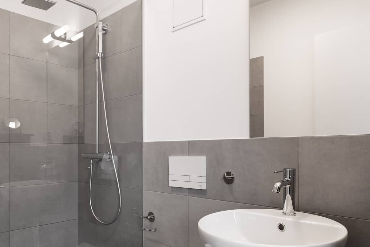 A modern bathroom with a glass-enclosed shower, a white toilet, and a dark wooden vanity with a white sink.