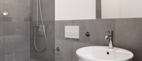 A modern bathroom with a glass-enclosed shower, a white toilet, and a dark wooden vanity with a white sink.