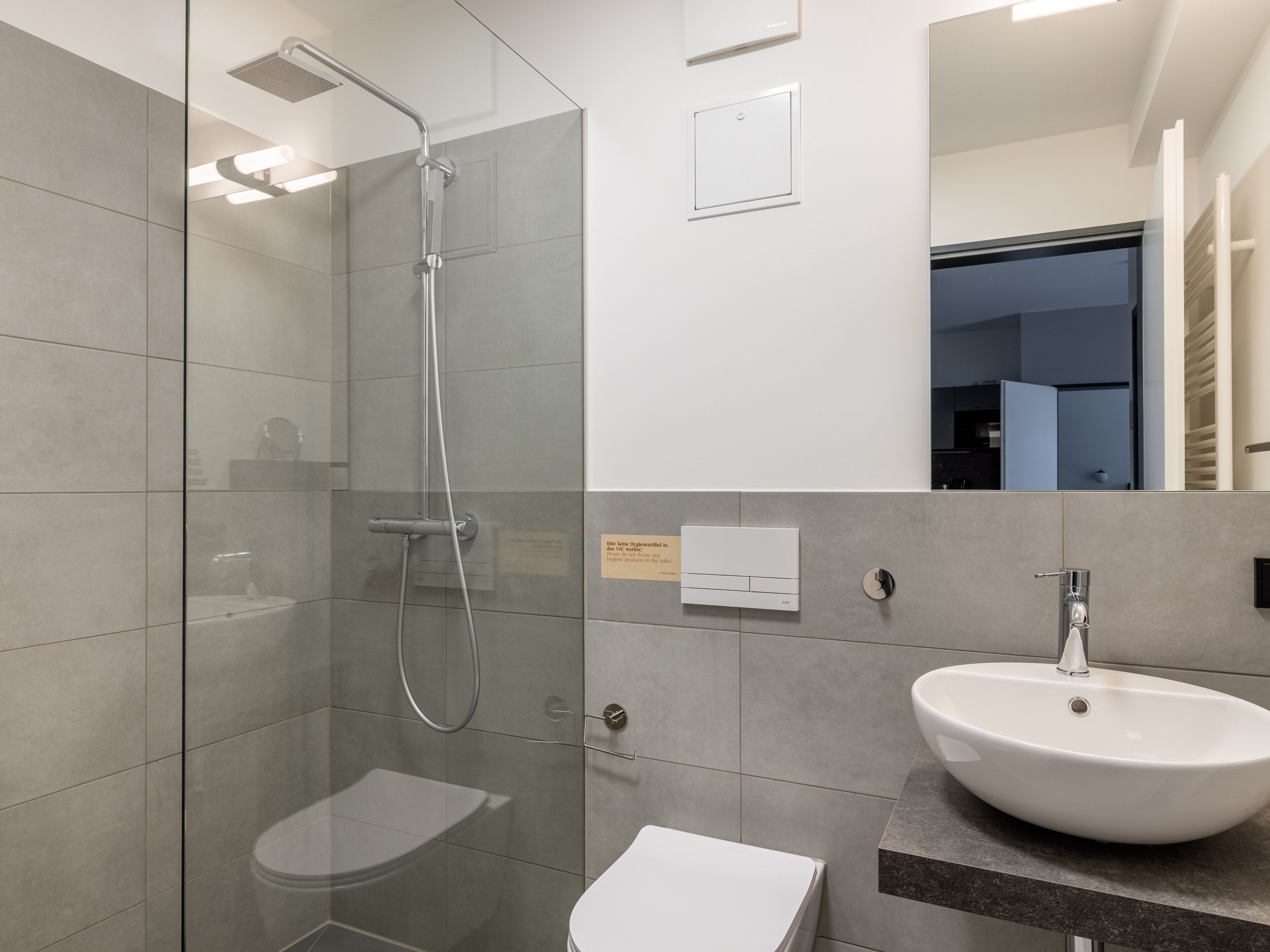 A modern bathroom with a glass-enclosed shower, a white toilet, and a large sink with a marble countertop.