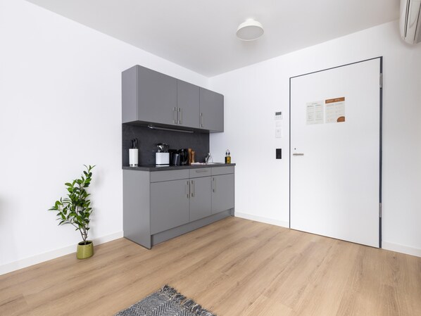 A modern kitchen with grey cabinets, a black countertop, and a wooden floor. - Limehome Bodenmais Bahnhofstraße (Bodenmais)