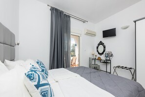 Relax in a spacious room with a large bed, flat-screen TV, and a small table with a lamp and mirror.
