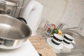 Kitchen area with stainless steel appliances, a kettle, and a large pot, along with a sink and a tiled backsplash.