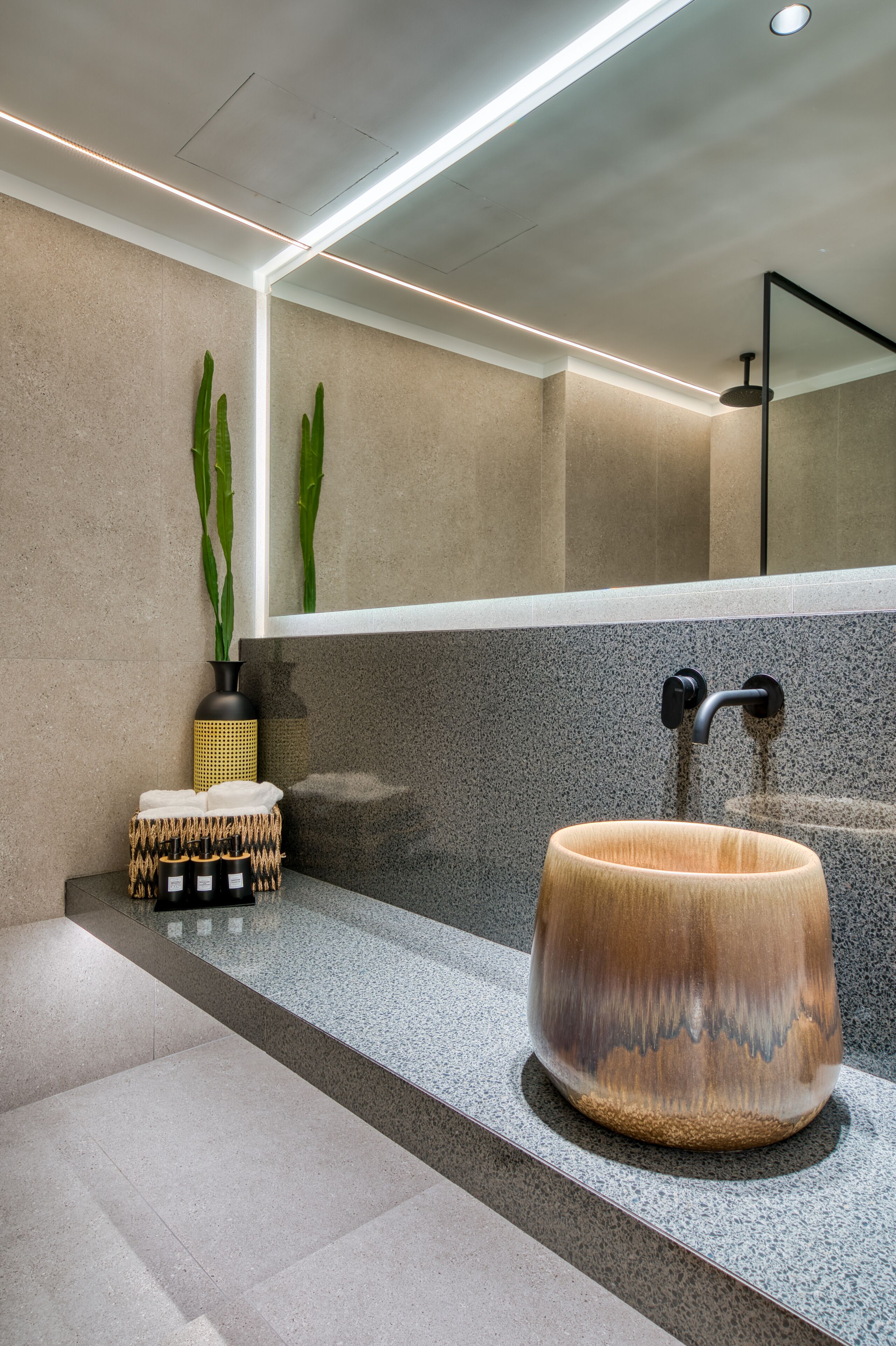 A modern bathroom with a large wooden basin, a black faucet, and a mirror above it.