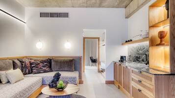 A modern living room with a sofa, a coffee table, and a kitchen area with wooden cabinets and a marble countertop.