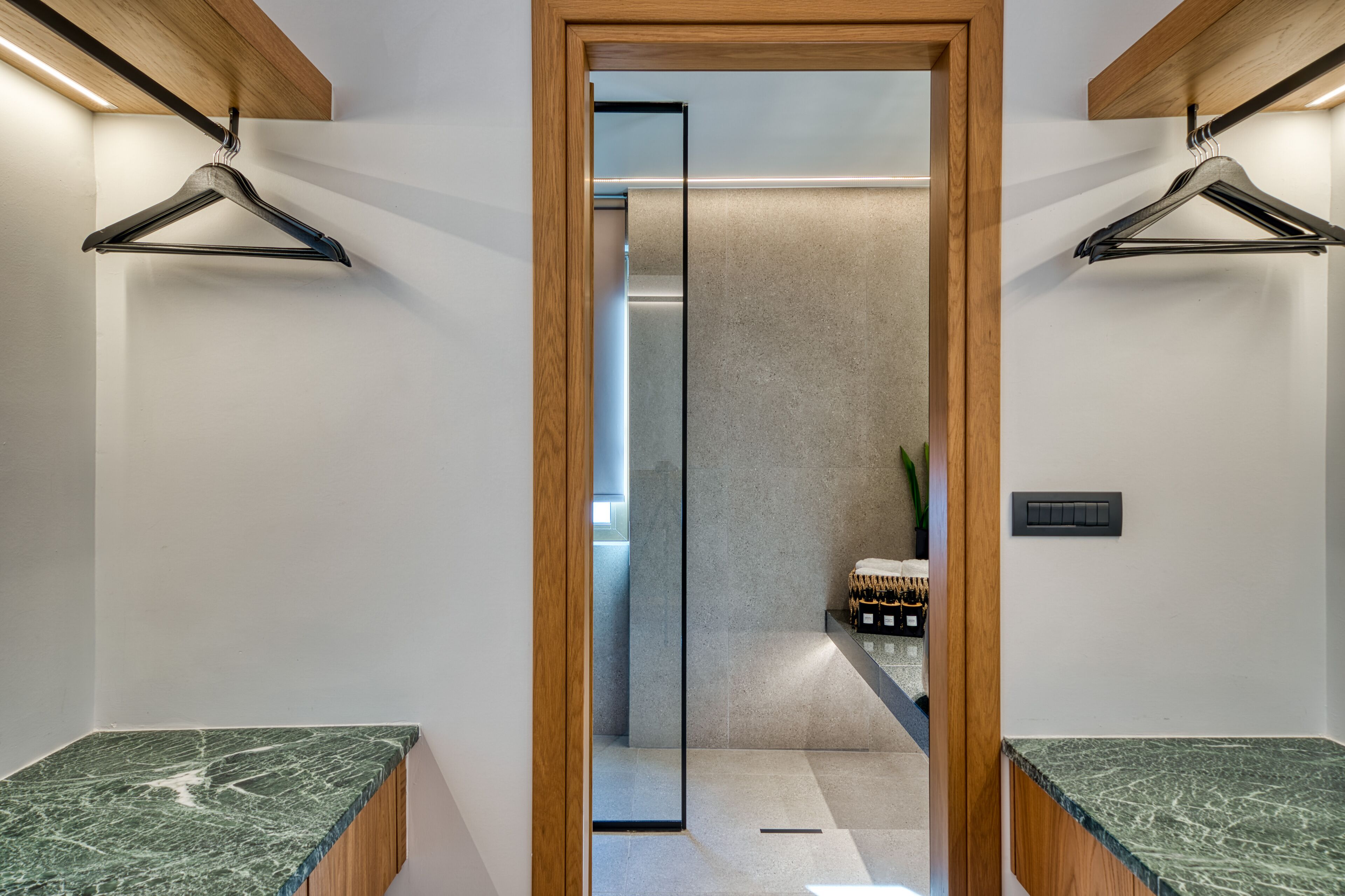A modern bathroom with two sinks, wooden ceiling beams, and a glass partition.