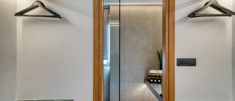 A modern bathroom with two sinks, wooden ceiling beams, and a glass partition.