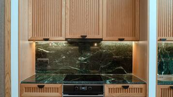 Una cucina moderna con mobili in legno, piano cottura nero e schienale in marmo.