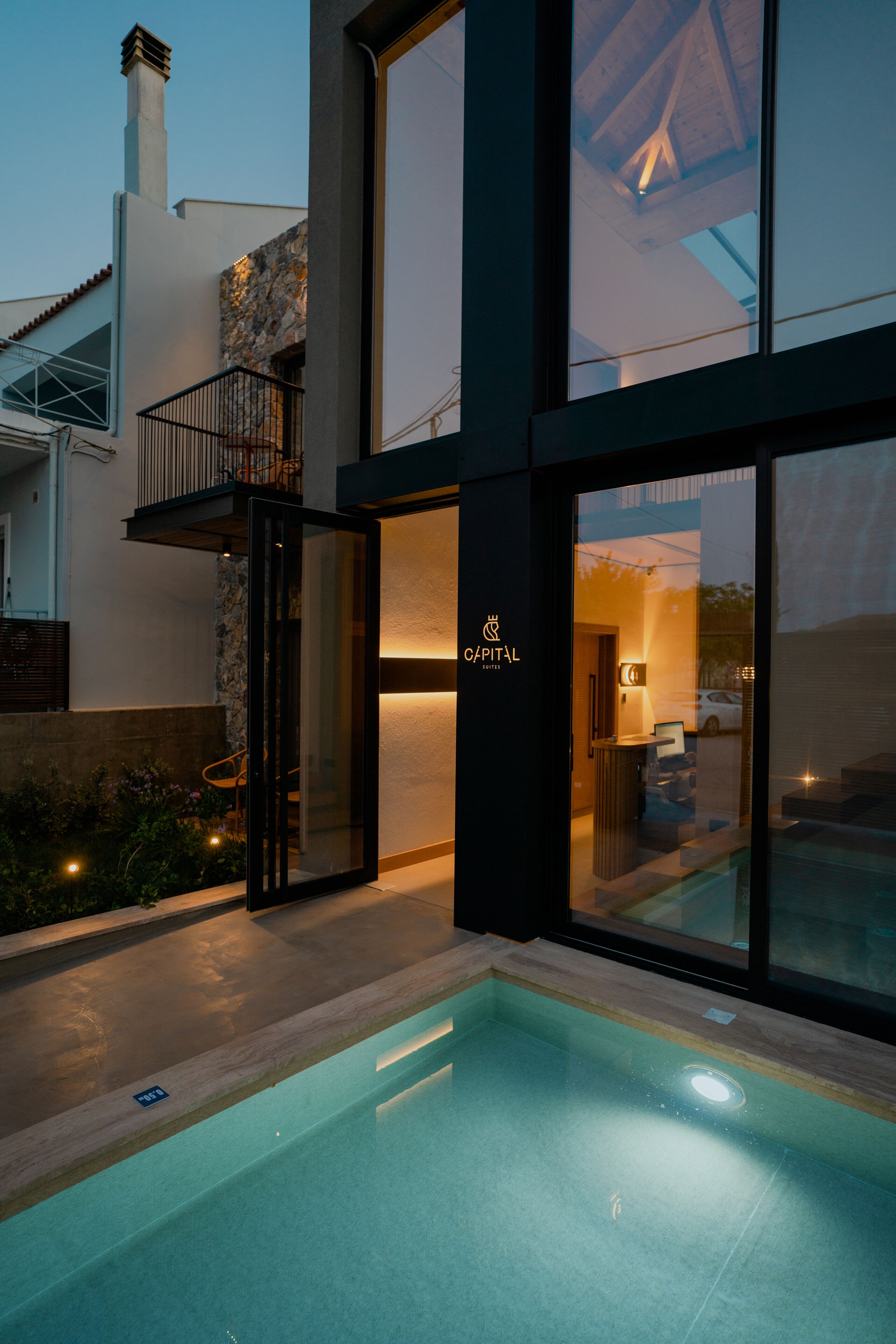 Un hôtel moderne avec une façade en pierre, de grandes baies vitrées et une piscine.