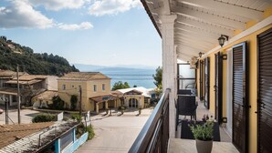 A balcony with a view of a coastal town, a covered walkway, and a potted plant. - The Seaview Corner Apartments by Konnect, Ipsos (Corfu)