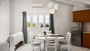 A modern kitchen with white cabinetry, a stainless steel refrigerator, and a dining area with a table set for four. - The Seaview Corner Apartments by Konnect, Ipsos (Corfu)