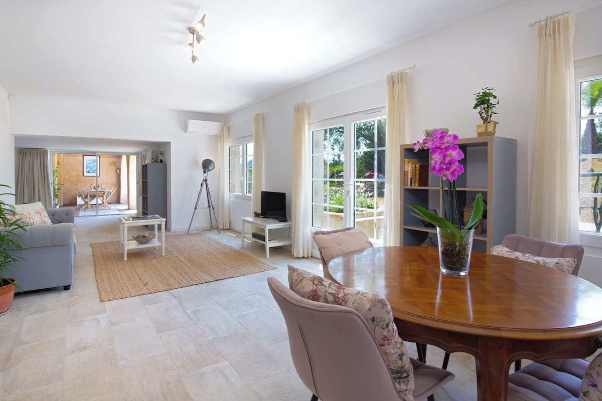 Ein geräumiges Wohnzimmer mit Essbereich, großen Fenstern und Blick ins Freie.