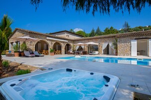 Una villa de piedra con piscina, zona de estar al aire libre y bañera de hidromasaje.