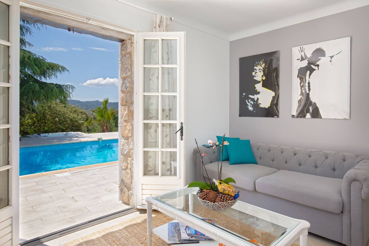 Ein Wohnzimmer mit einem Glastisch, einem grauen Sofa und zwei Wandbildern.