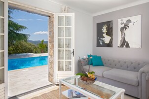 Una sala de estar con una mesa de centro de vidrio, un sofá gris y dos obras de arte en la pared.