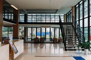A spacious lobby with a staircase, large windows, and a reception desk. - Grace Hotel (Van Xuan)