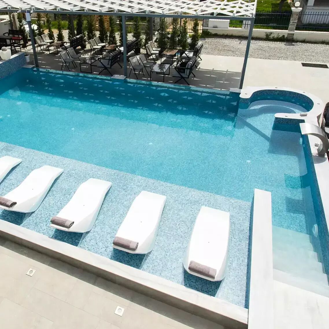 A pool with lounge chairs and a pergola.
