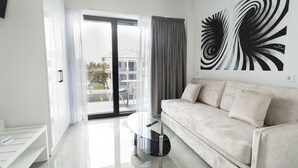 Una sala de estar moderna con un sofá, una mesa de centro de vidrio y un cuadro abstracto grande.