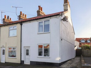 A two-story residential building with a white facade, multiple chimneys, and satellite dishes. - 9 North End (Bridlington)