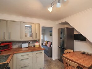 A compact kitchen with a refrigerator, microwave, and a wooden dining table. - 9 North End (Bridlington)