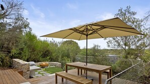A wooden deck with a table and bench, a stone wall, and a fire pit.
