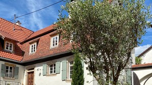 A traditional European building with a tiled roof, a staircase leading to the entrance, and a potted tree in the foreground. - Nußriegel vacation apartment in a historic setting on the wine route (Bad Dürkheim)