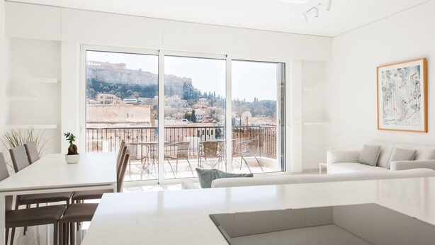 A modern, bright living room with a large sliding glass door leading to a balcony with a city view. - Athens Observatory Suite - Breathtaking views of the Acropolis (Athina)