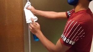 A person cleaning a mirror with a cloth and spray bottle. - Oxford Hotel Powai (Mumbai)