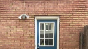 Una puerta azul con marco blanco, una ventana pequeña y un timbre.