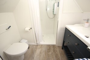 A bathroom with a toilet, shower, and vanity with drawers. - Zen Cottage, Cullen - Sleeps 4, Garden & Pets Ok (Buckie)