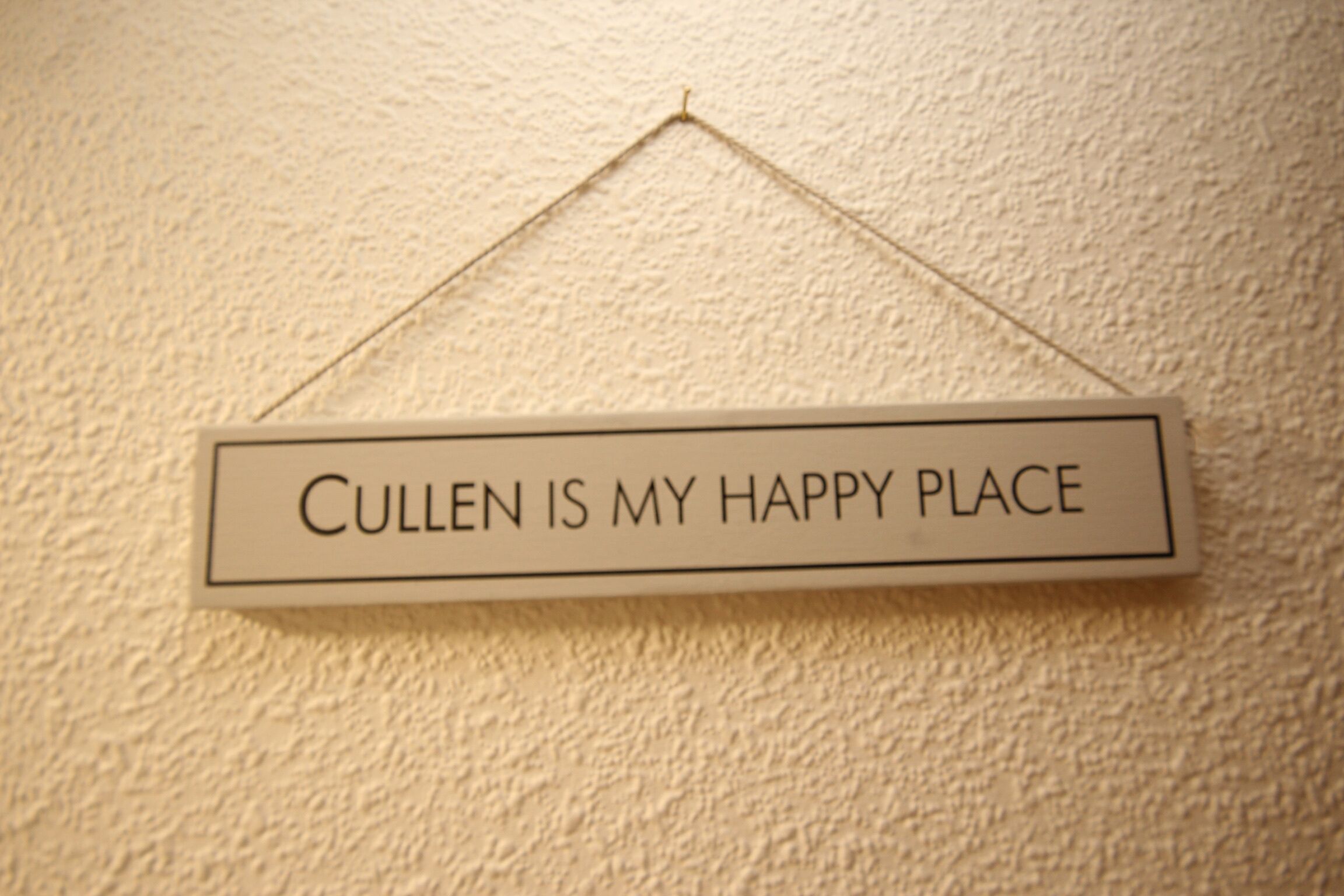Un cartel con el texto 'Cullen is my happy place' colgado en una pared con textura.