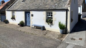 A white cottage with a blue door, numbered 151, and a small bench outside. - Zen Cottage, Cullen - Sleeps 4, Garden & Pets Ok (Buckie)