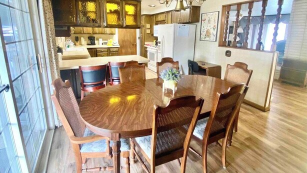 A dining area with a wooden table and chairs, a chandelier, and a kitchen in the background. - Roomy Midtown Home-Large and Central to Everything (Pocatello)