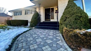 A two-story house with a covered front porch, a brick exterior, and a snow-covered driveway. - Roomy Midtown Home-Large and Central to Everything (Pocatello)