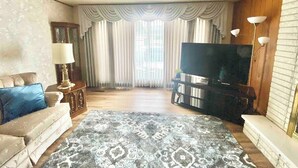 A living room with a sofa, a television, a coffee table, and a patterned rug. - Roomy Midtown Home-Large and Central to Everything (Pocatello)