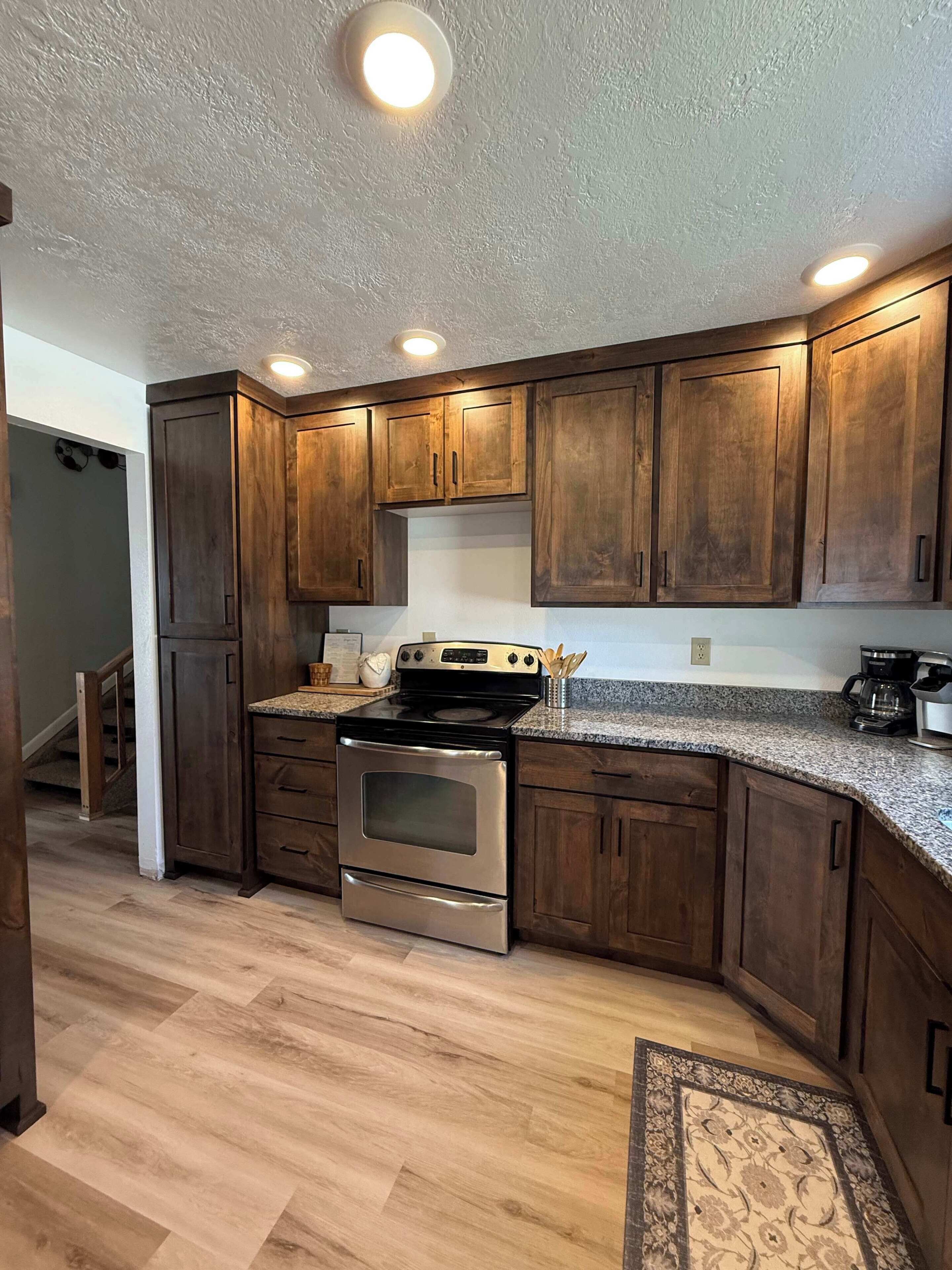 A kitchen with wooden cabinets, a stainless steel stove, and granite countertops.