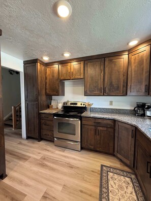 A kitchen with wooden cabinets, a stainless steel stove, and granite countertops.