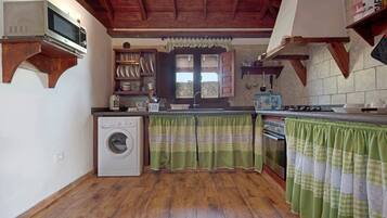 A kitchen with wooden beams, a washing machine, a microwave, and a stove.