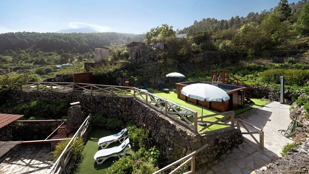 Un complexe hôtelier doté d’un pont en pierre, de chaises longues, d’une piscine et offrant une vue sur une montagne.