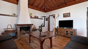 Un salon doté d’une cheminée, de meubles en bois, d’un téléviseur et d’un plafond haut.