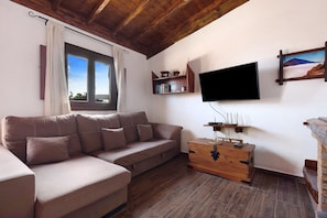 Un salon avec un canapé, un meuble en bois, une télévision et une cheminée.